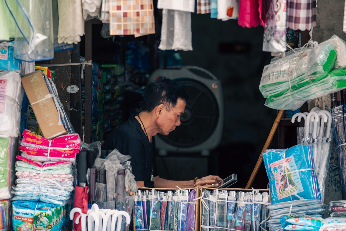A shopkeeper checking a phone in a small shop